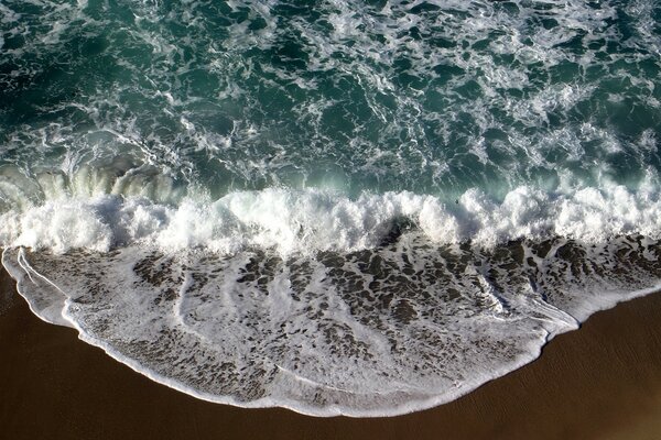 Schiuma di mare dalle onde sulla riva