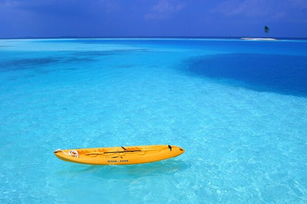 Azurblaues Wasser mit Boot und Palme in der Ferne