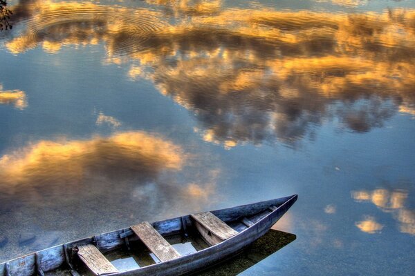 Barco en el fondo del reflejo de las nubes flotantes