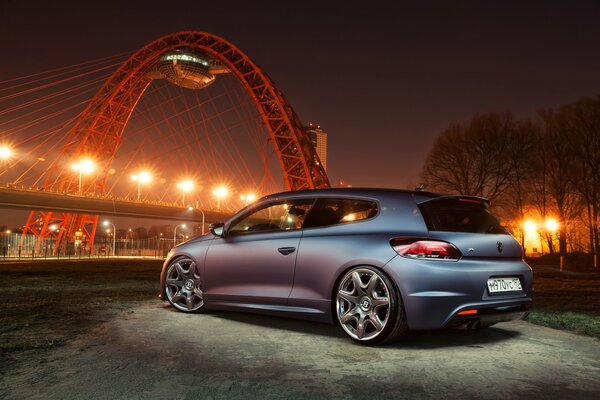 Volkswagen in gray in the middle of the bridge and the night city