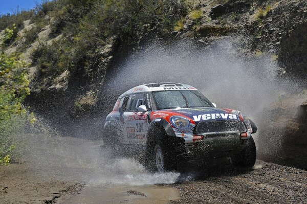 Mini Cooper conduce a través de un charco formando salpicaduras