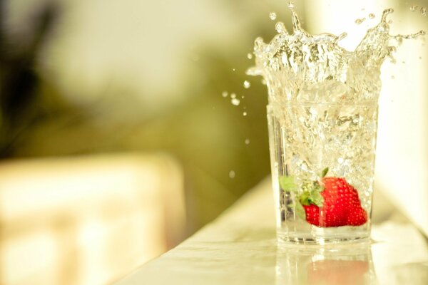 Strawberries with splashes fall into a glass