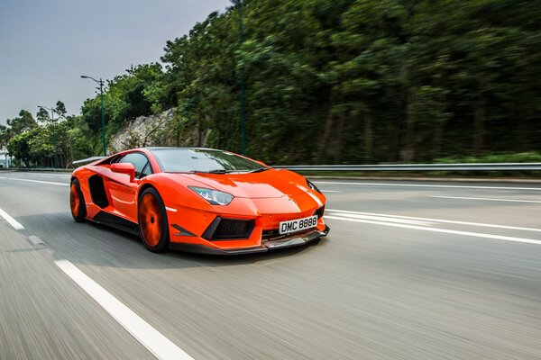 A red Lamborghini is racing down the road