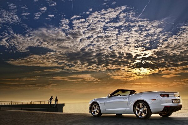 Chevrolet Camaro blanc cabriolet sur fond de coucher de soleil