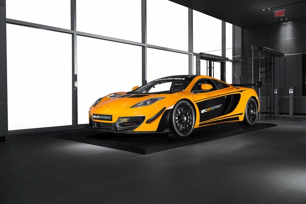 The orange mclaren mp4-12c gt car is standing indoors