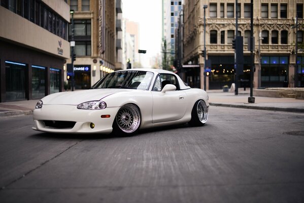 Mazda Miata bianca sullo sfondo di una strada cittadina