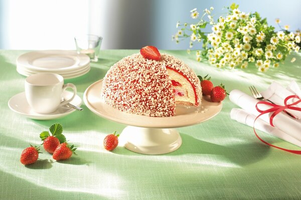 Pastel de fresa, flores y vajilla