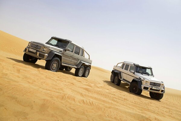 Weiße und graue GELÄNDEWAGEN stehen im Sand