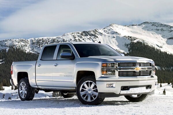 Silver Chevrolet Silverado on the background of snow-capped mountains