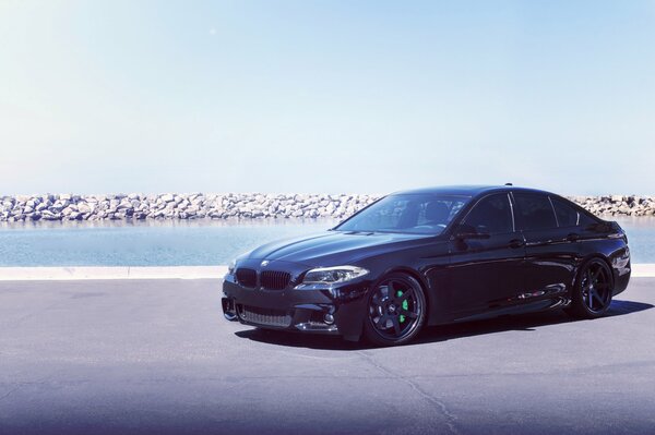 BMW black on the road near the shore