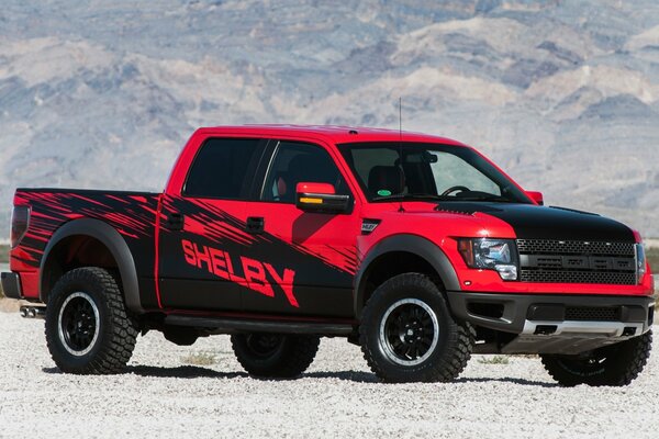 Fondo de pantalla con una camioneta Shelby roja y negra en medio de montañas nevadas