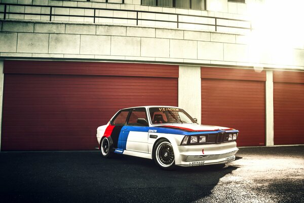 BMW white-blue-coasno-black color stands next to the garages