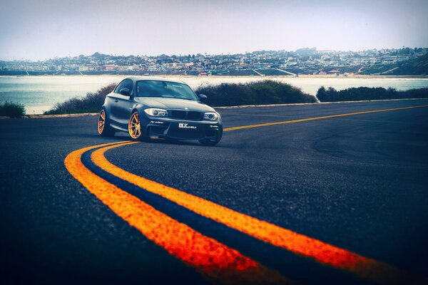 A black BMW with yellow wheels rushes along the highway