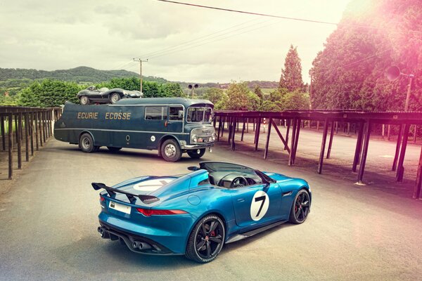 Blue jaguar and bus on city background