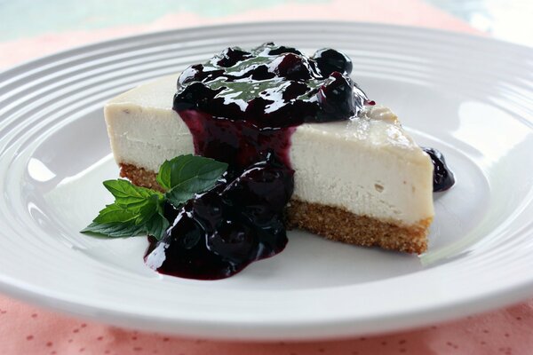 Rebanada de tarta de queso con mermelada de cereza y hoja de menta