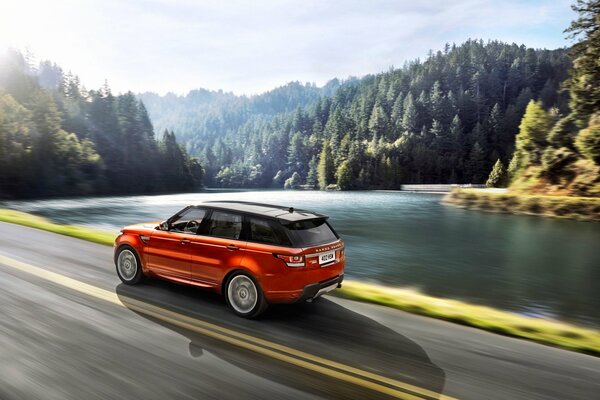 Paesaggio della foresta con lago e Land rover Sport vista dal lato