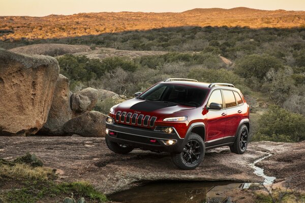 JEEP CHEROKEE SULLE ROCCE AI RAGGI DEL TRAMONTO