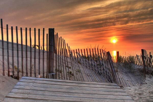 Sunset on the background of a falling fence