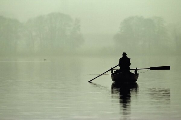 Fog on the lake. fisherman in a boat