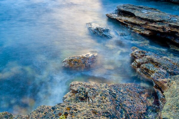 Riva di pietra vicino all acqua blu