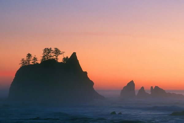 Coucher de soleil rouge sur les vagues de la mer et les rochers qui sortent de l eau