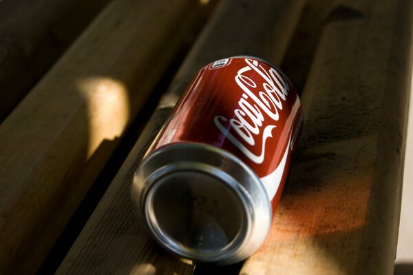 Una lata de Coca-cola solitaria en un banco