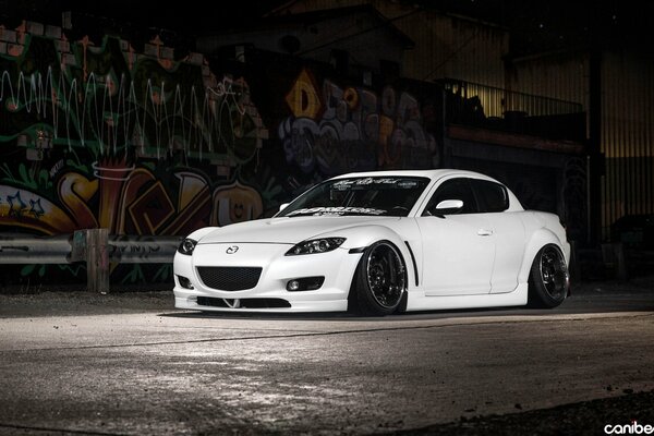 Biała Mazda Rx-8 przy malowanej ścianie