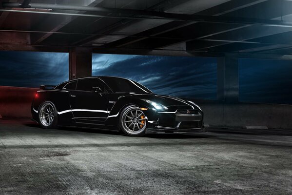 Black Nissan in a dark parking lot