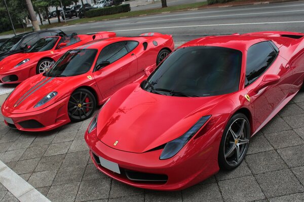 Czerwone supersamochody ferrari 458 spider zaparkowane przy drodze