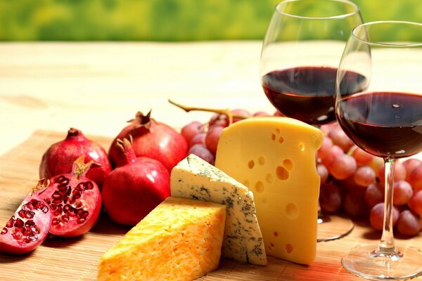 Deux verres de vin avec du fromage, des raisins et de la Grenade