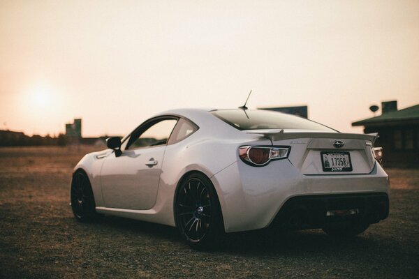 A white Subaru car is on the road