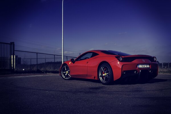 Red Italian Ferrari on the road in the evening