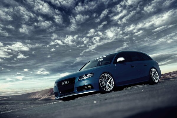 Blauer Audi auf Himmelshintergrund mit Federwolken