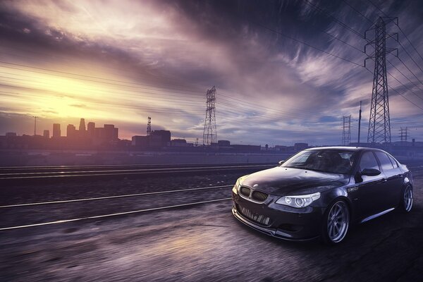 A black car rides against the background of the evening city along the rail