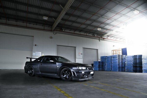 Ein schwarzer Nissan r34 steht im Hangar