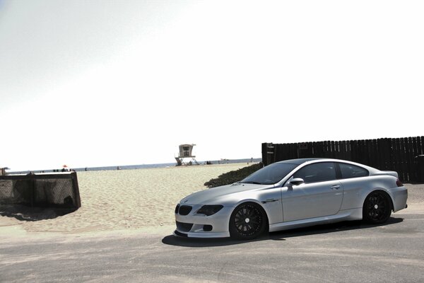 Plata BMW M6 bajo el cielo en la playa