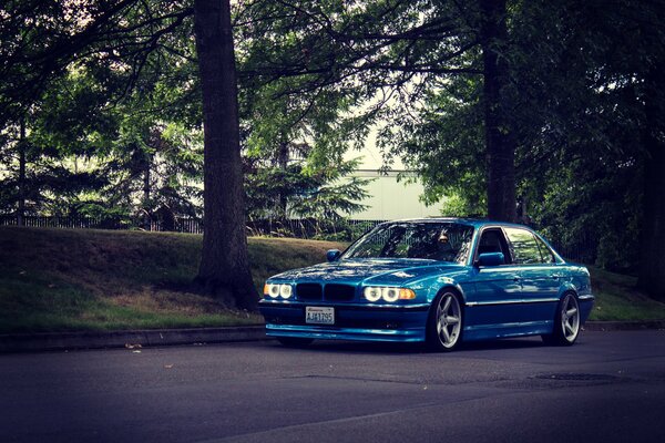 Une BMW bleue tuning garée près de la route