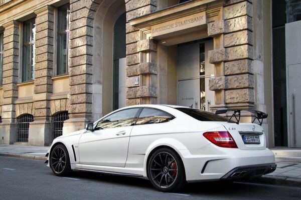 A white Mercedes Benz is driving around the city