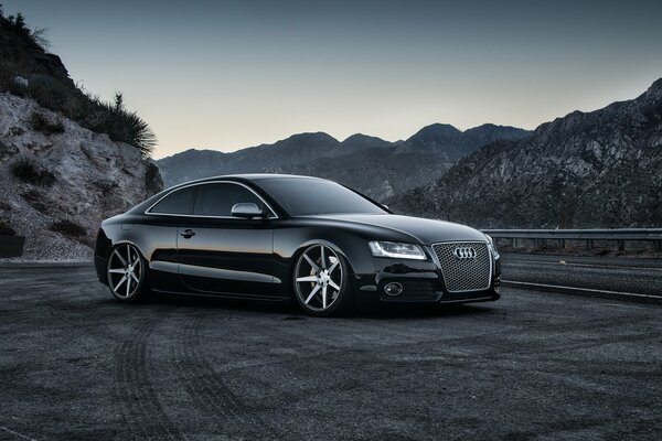 Audi negro entre las colinas en la carretera