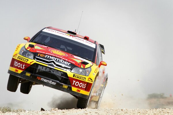 Front view of a car riding on two wheels participating in a rally