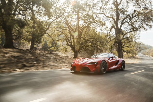 A red car rushes down the road