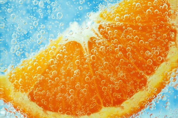 Una rodaja de naranja bajo el agua en burbujas