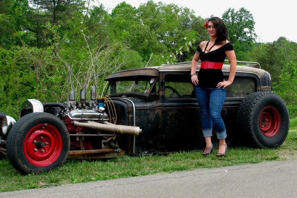 Hermosa chica en jeans de pie cerca del coche en la naturaleza