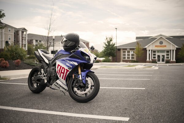 Blaue Yamaha mit Helm auf leerem Parkplatz abgestellt