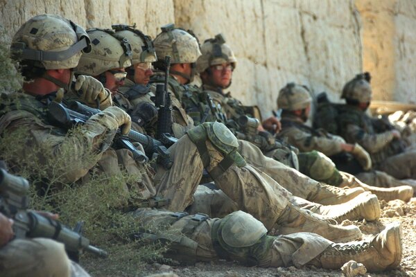 Image of soldiers resting with machine guns in their hands