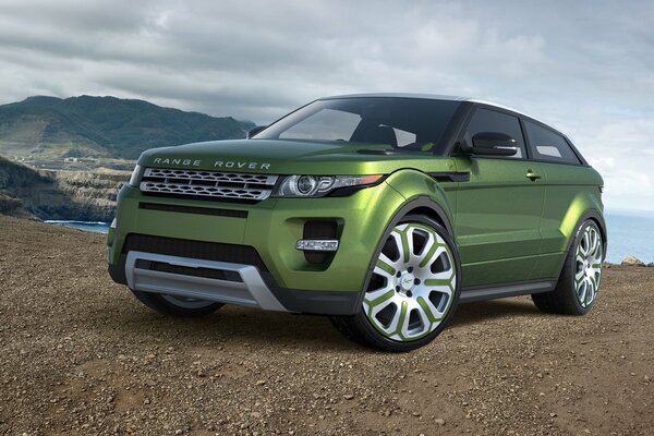 Green Land Rover car on the background of the sky and mountains