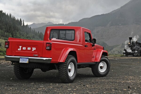 Camioneta Jeep J-12 en color rojo vista trasera en medio de las montañas