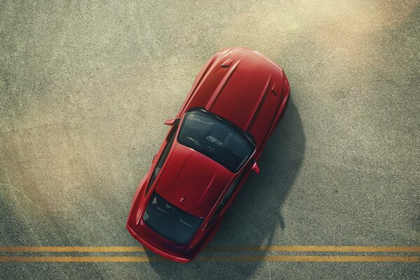 A beautiful red car is standing on the road with yellow stripes