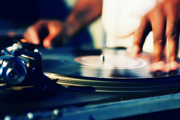 Photo of the hands of a DJ who plays on vinyl records