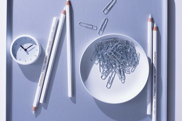 A plate with paper clips and five pencils